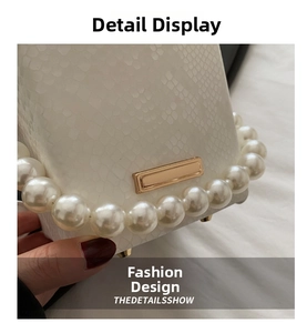 Close-up of white embossed leather bag with large pearl handle and gold metal clasp
