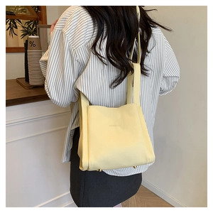 Close-up of lychee-textured light yellow bucket bag featuring brand logo and metal feet
