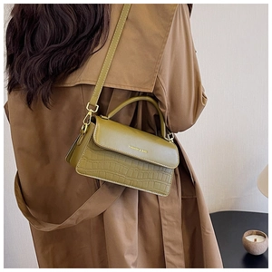 Detailed macro view of olive green bag with crocodile pattern and golden hardware accents