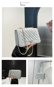 Detail of silver chevron quilted crossbody bag with gold metallic clasp and chain strap