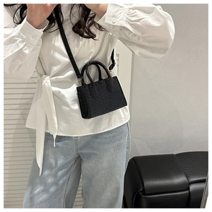 Close-up of black textured leather mini square bag with elegant gold hardware and top handle