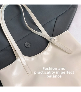Detail of creamy white faux leather tote with adjustable silver buckle on strap