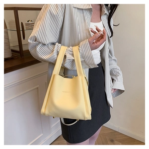 Detail of light yellow lychee pattern leather tote bag with brand logo and gold feet
