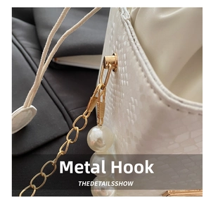 Detail of white snakeskin texture bucket bag with gold hardware and pearl strap accents