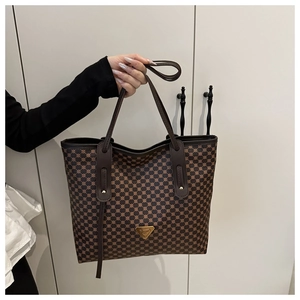 Détail du sac cabas à carreaux avec logo en métal triangulaire et anses en cuir brun