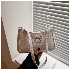 Detail of woven crescent shoulder bag with snake pattern trim and golden bow buckle