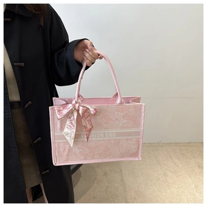 Detail of pink fabric tote bag with a floral scarf handle and printed decorative stripe