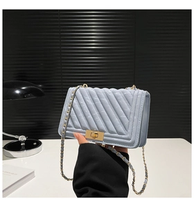 Close-up of light blue quilted crossbody bag featuring a golden twist-lock and chain strap