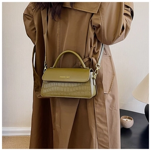 Detail view of olive green bag with crocodile pattern and gold brand lettering