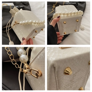Detailed view of white snakeskin bucket bag with pearl handle and golden metal studs