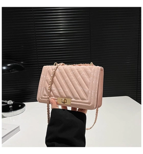 Close-up of pink quilted crossbody bag featuring a golden chain strap and metal turn-lock