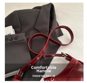 Detail of dark red glossy faux leather bag with metal eyelets and shoulder strap