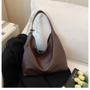 Detailed view of woven leather texture and fashion zipper pull on dark brown tote bag