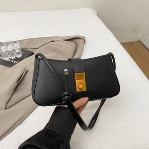 Minimalist black faux leather baguette bag with golden square lock in a stylish setting
