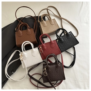 Overhead view showing textured woven mini handbags in six different colors on linen fabric
