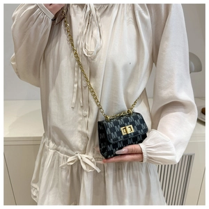 Detail of mini dark grey crossbody bag with M-pattern and golden chain strap
