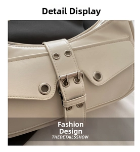 Close-up of cream leather shoulder bag with silver buckles and eyelet strap details