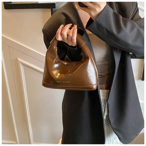 Detail of dark coffee glossy leather handbag featuring FASHION & BAGS printed logo