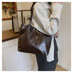 Dettaglio borsa tote marrone scuro lucida con trama naturale e tracolla regolabile