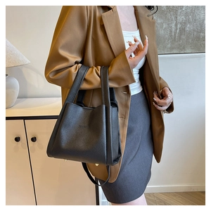 Detail of black lychee grain leather tote bag with gold protective base studs