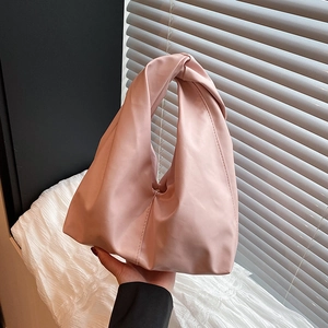 Pink pleated bucket bag with a knotted handle shown in a stylish hand-held pose