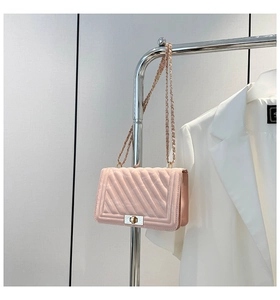 Detail of pink quilted chain bag featuring a metallic turn-lock and leather-woven strap