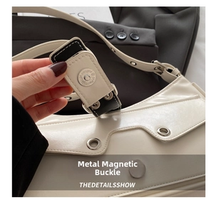 Close-up of premium silver magnetic hardware on a white vintage leather shoulder bag