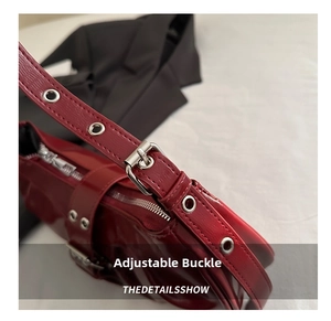 Detail of red patent leather shoulder bag with adjustable metal buckle and eyelets