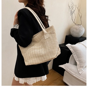 Close-up of beige woven tote bag showing herringbone texture on a model's shoulder
