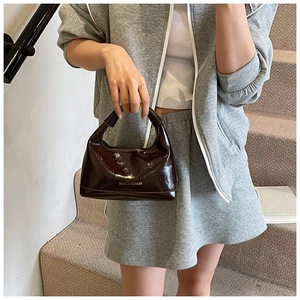 Detail view of dark brown leather pillow bag with Fashion & Bags lettering and top handle