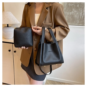 Detail of black pebbled leather bucket bag set with bottom studs and brand embossing