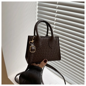 Detail of dark brown woven texture handbag with golden hardware and double handles