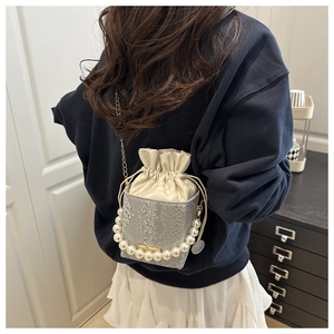 Close-up of snake skin textured bucket bag with pearl handle and metal chain strap