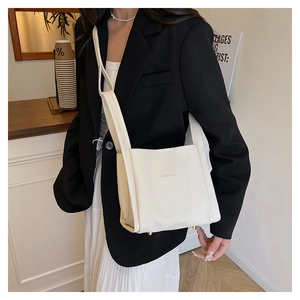 Close-up of white lychee pattern leather shoulder bag with gold base studs and logo detail