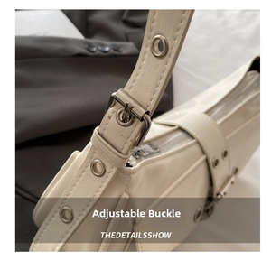 Close-up of the silver buckle and metal eyelets on the beige leather bag strap