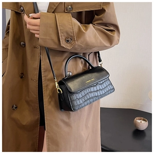 Detail of black faux leather mini square bag with crocodile pattern and gold hardware