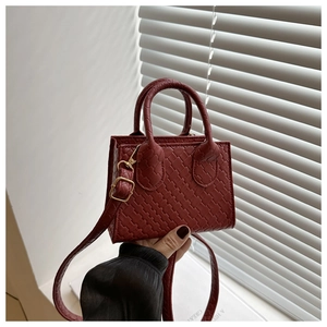 Close-up of wine red mini tote bag with woven texture and gold metal hardware detail