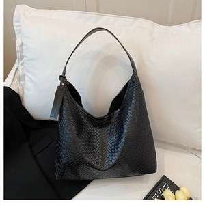Detail of black woven hobo bag with snakeskin embossed texture and leather logo tag