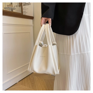 Detail of creamy white pebble leather handbag with gold metal feet and brand lettering