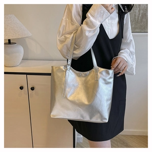Borsa tote in pelle argento portata a spalla mostra la capienza e la trama metallica
