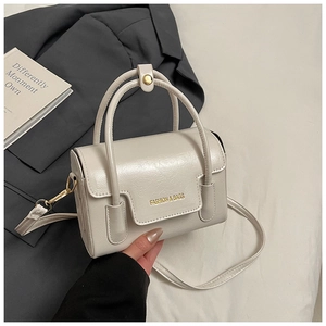 Détail d'un petit sac à main blanc crème en cuir brillant avec logo doré et bandoulière