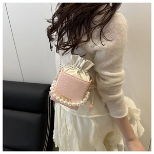 Detail of pink snake-pattern leather bucket bag with large pearl handle and chain