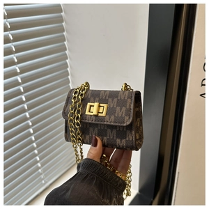 Detail of a brown leather shoulder bag with gold chain and monogram pattern