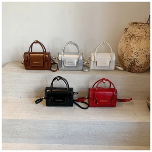 Cinq sacs à main miniatures en cuir de couleurs assorties sur une plateforme en pierre