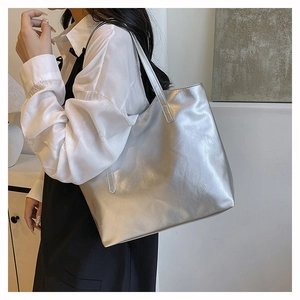 Dettaglio della borsa tote argento metallizzato con texture lucida e spalline sottili
