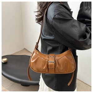 Detail of caramel pleated patent leather shoulder bag with vintage metal buckle