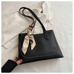 Détail d'un sac cabas en cuir noir avec surpiqûres blanches et foulard en soie décoratif