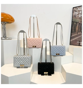 Detailed view of four V-quilted small square bags with metal turn-lock and chain straps