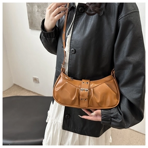 Detail of caramel brown glossy shoulder bag with pleated texture and metal belt buckle