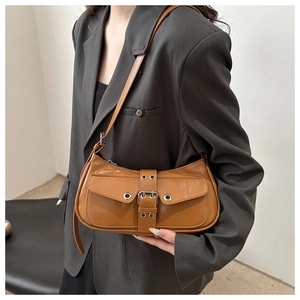 Detail of brown faux leather shoulder bag with vintage buckle on polished surface
